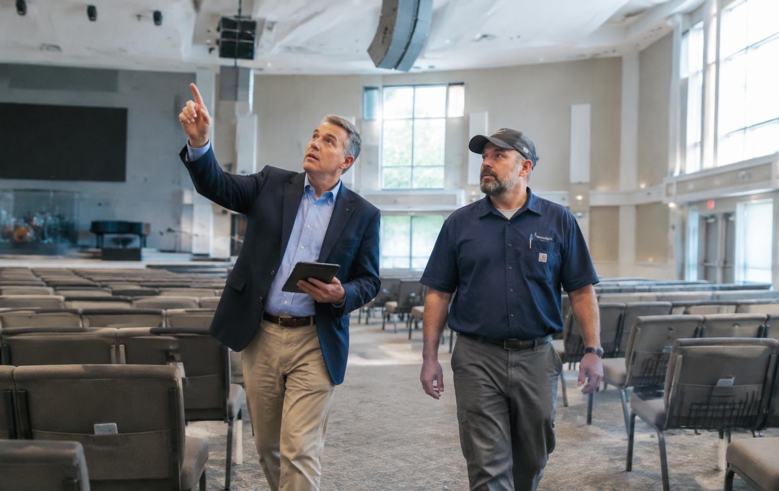 Consultant pointing out ceiling speakers to a facility manager during a walkthrough